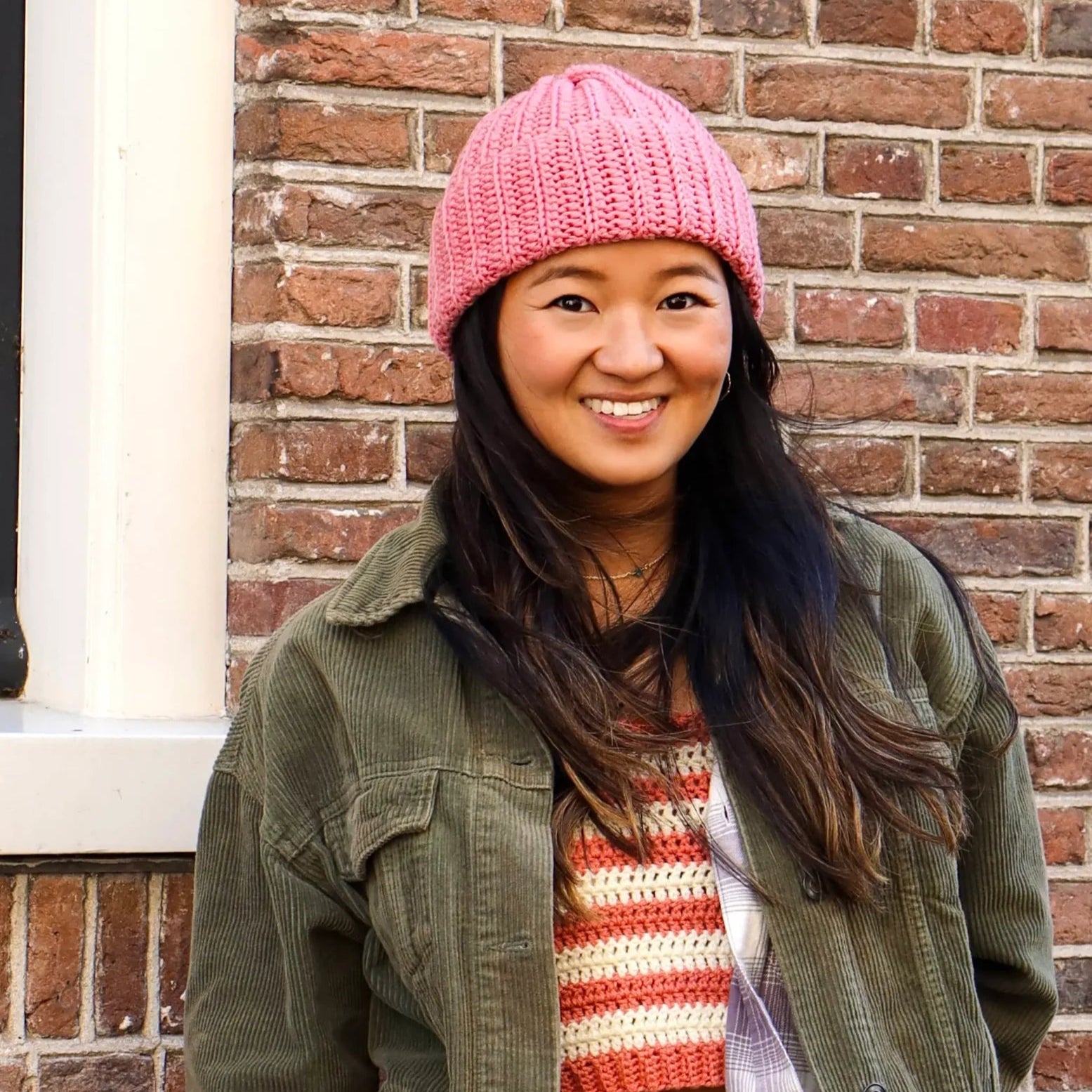 De vrouw op de foto draagt een gehaakte roze muts van Haakspot.