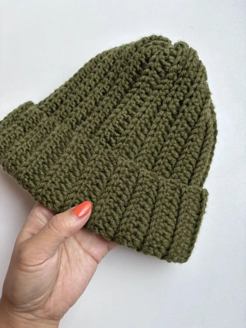 Een gehaakte legergroene muts van Haakspot op een witte achtergrond.